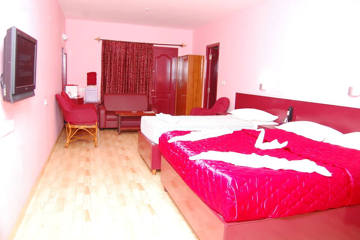 A hotel room with a bed, a desk, a chair, a wardrobe, and a television.