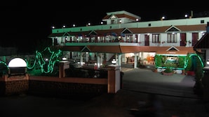 A two-story building with a balcony, a covered outdoor seating area, and a well-lit entrance. - Apple Valley (Kodaikanal)