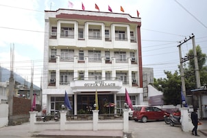 A multi-story hotel named 'Hotel Gupta Palace' with balconies, a gated entrance, and a parking area.