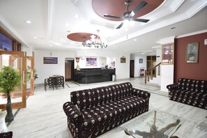 Amplia sala de estar con sofá, una mesa de centro, ventilador de techo y candelabro.