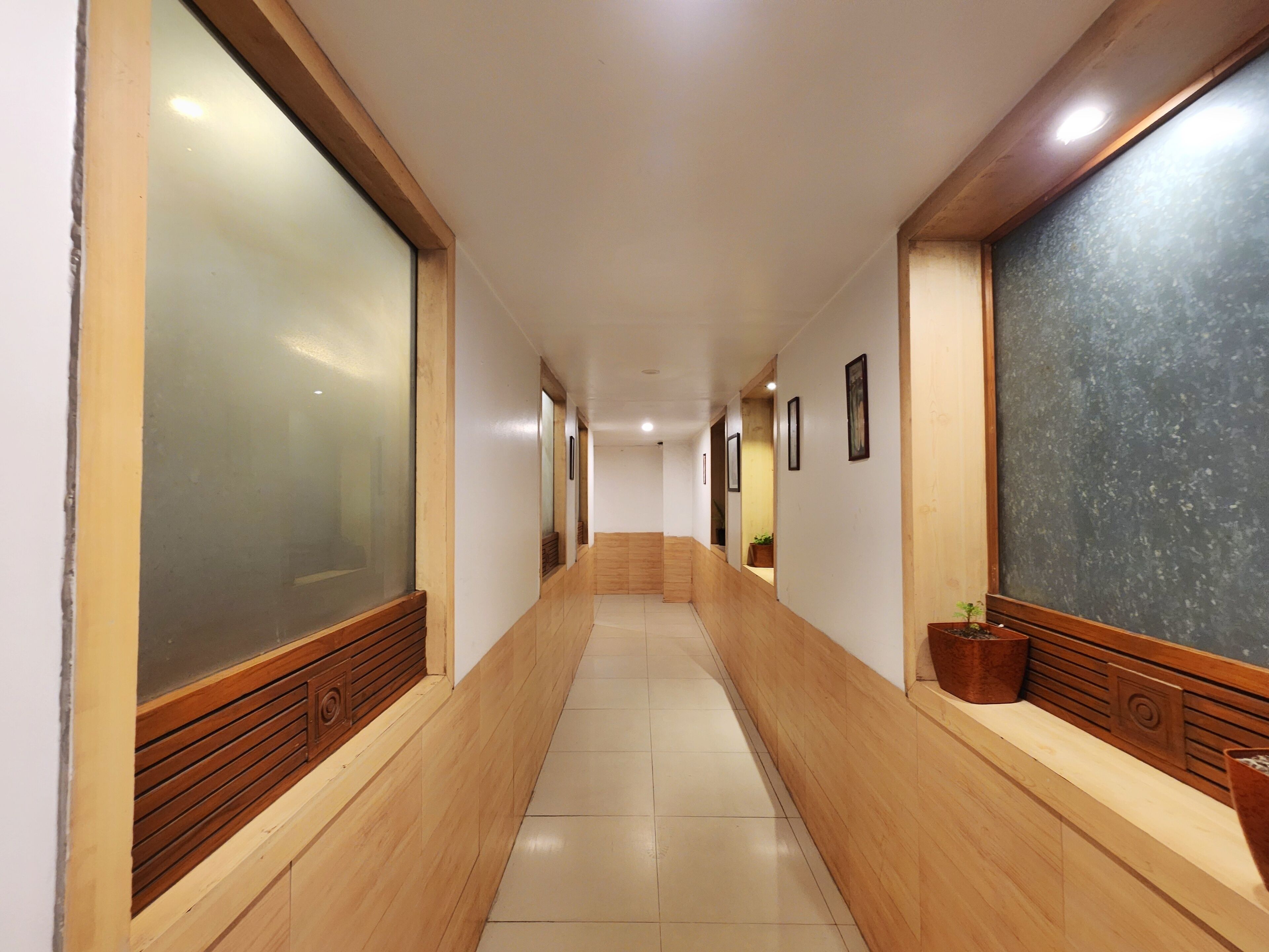 A hallway with wooden paneling, a tiled floor, and framed pictures on the walls.