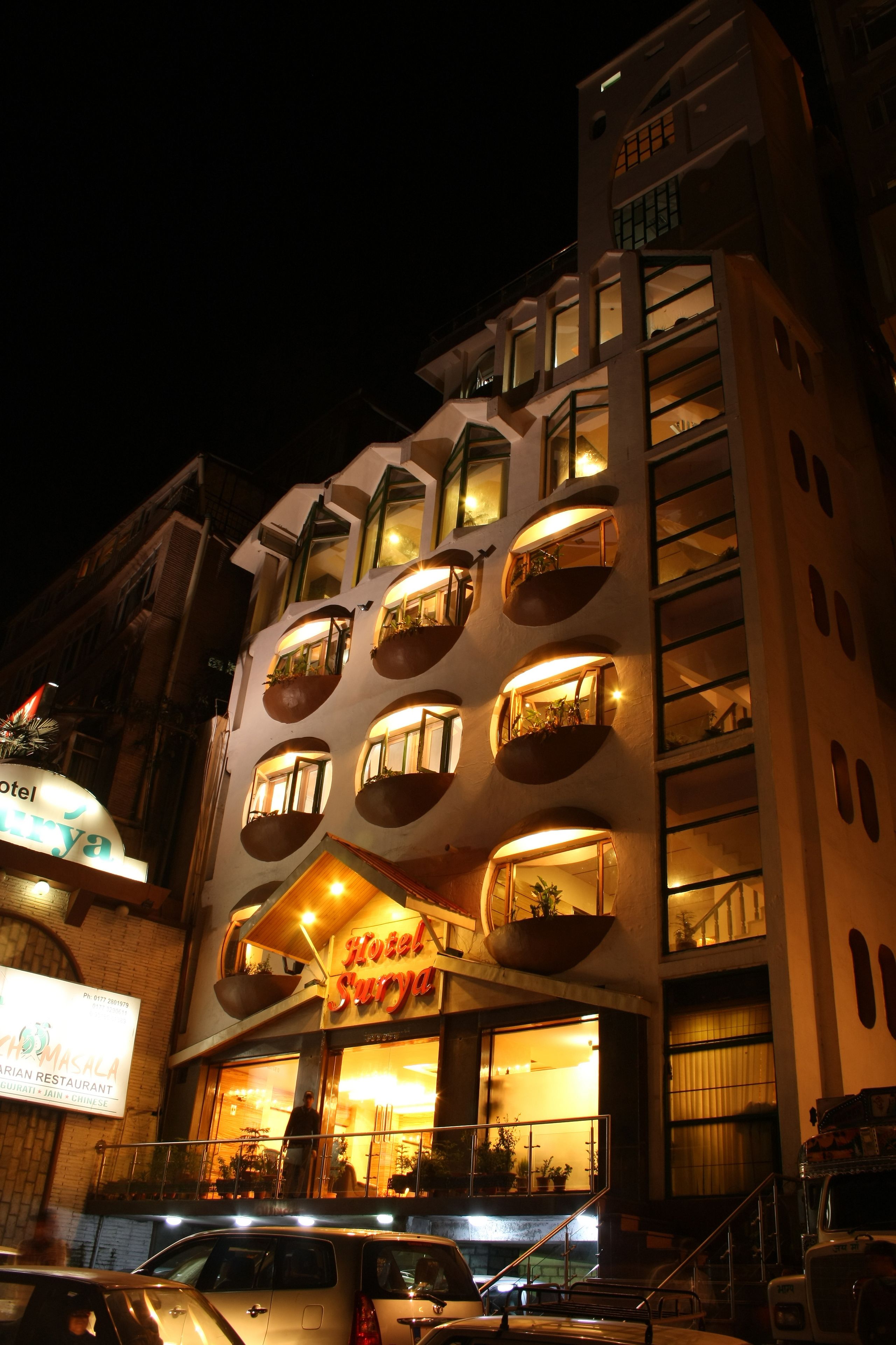 A hotel with multiple balconies, a sign indicating it is a hotel, and a visible entrance with a staircase.