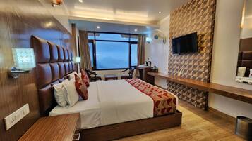 Een moderne hotelkamer met een groot bed, een bureau, een televisie en uitzicht op de bergen.