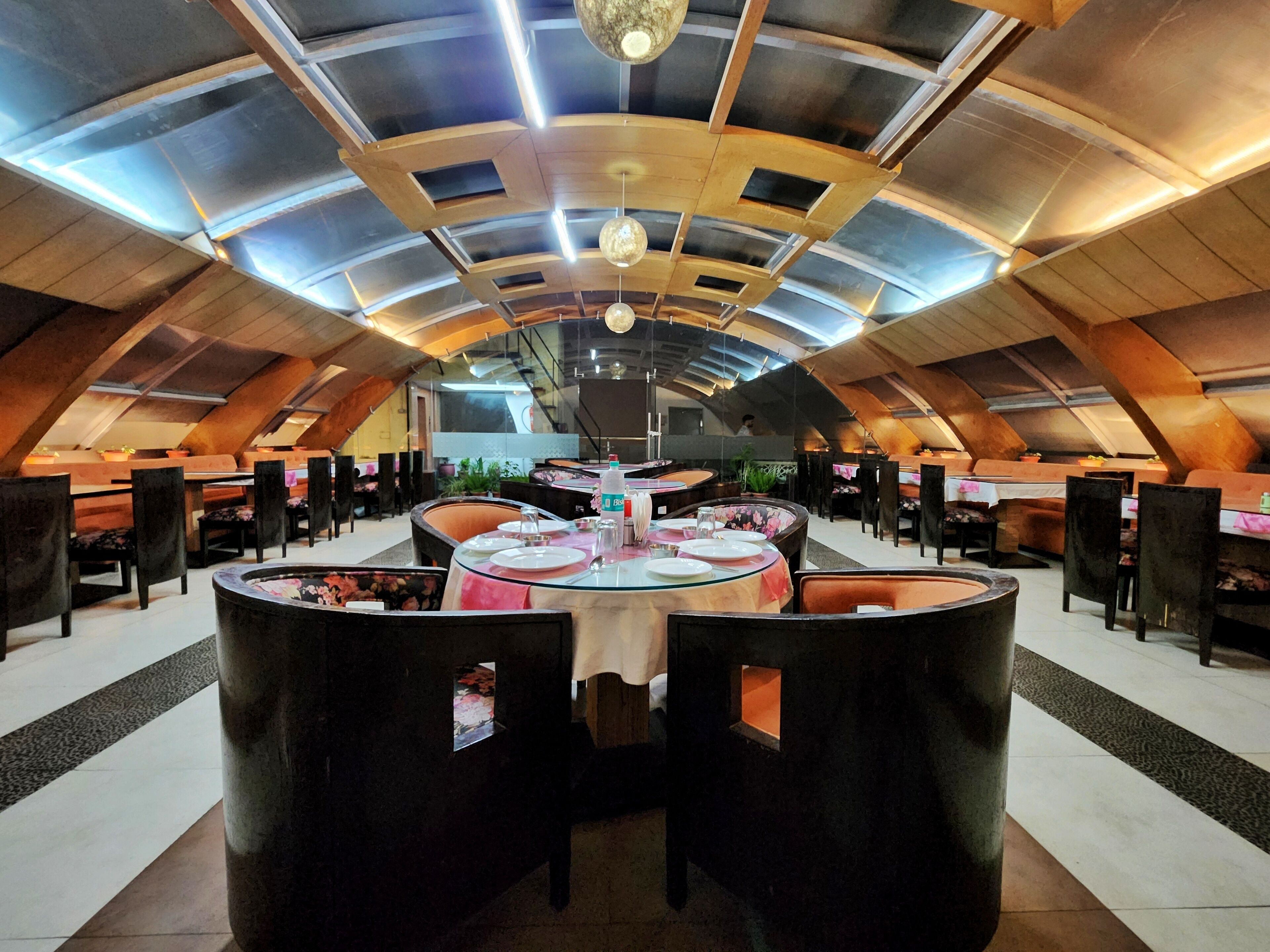 Un ristorante con soffitto alto a volta e un tavolo rotondo centrale circondato da sedie.