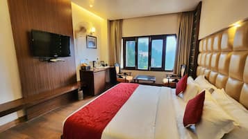 Quarto de hotel com cama, escrivaninha, televisão e janela com vista.
