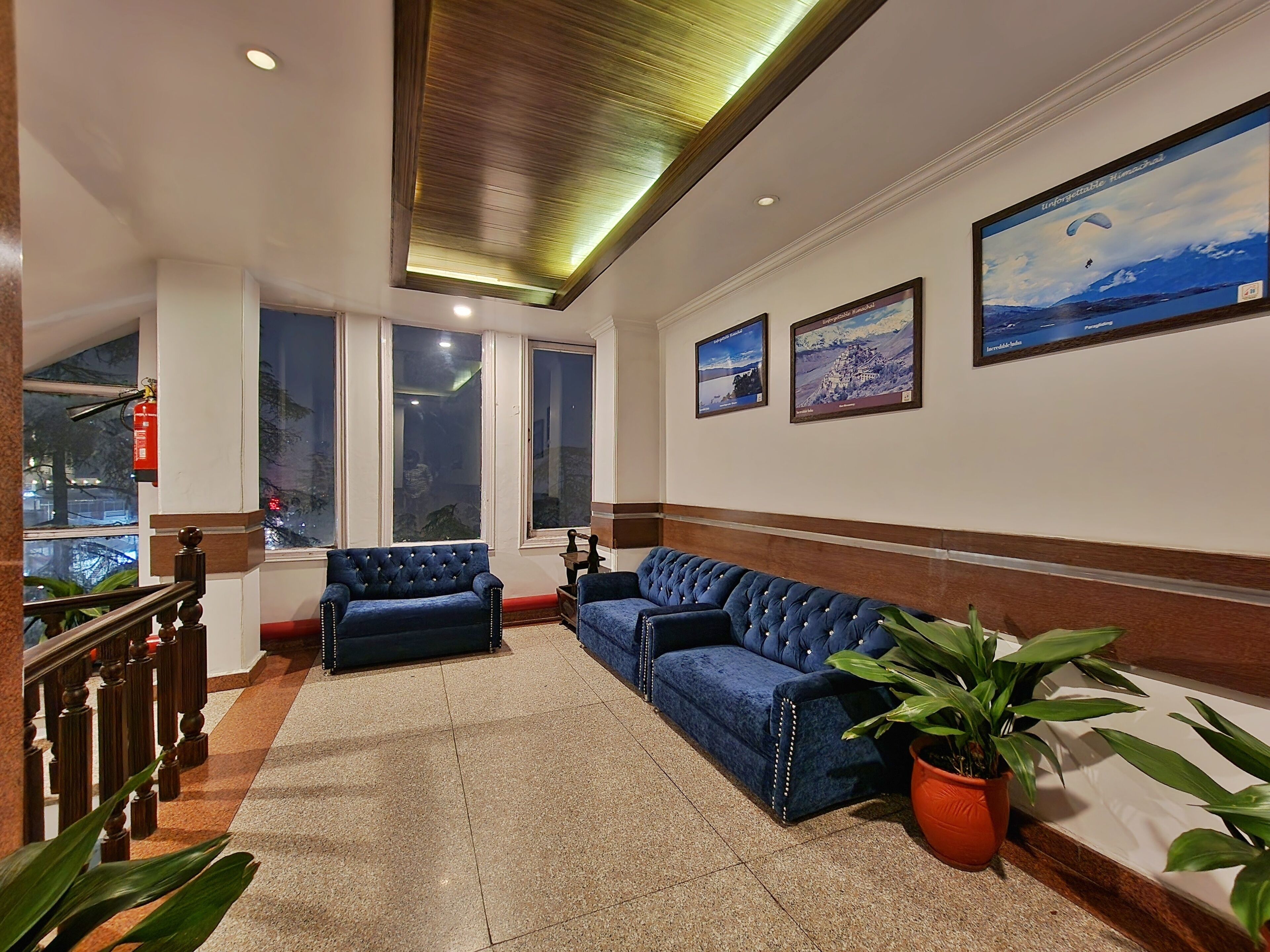 A hotel lobby with a seating area, large windows, and framed pictures on the wall.