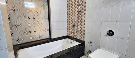 A modern bathroom with a large bathtub, a separate sink, and a shower area.