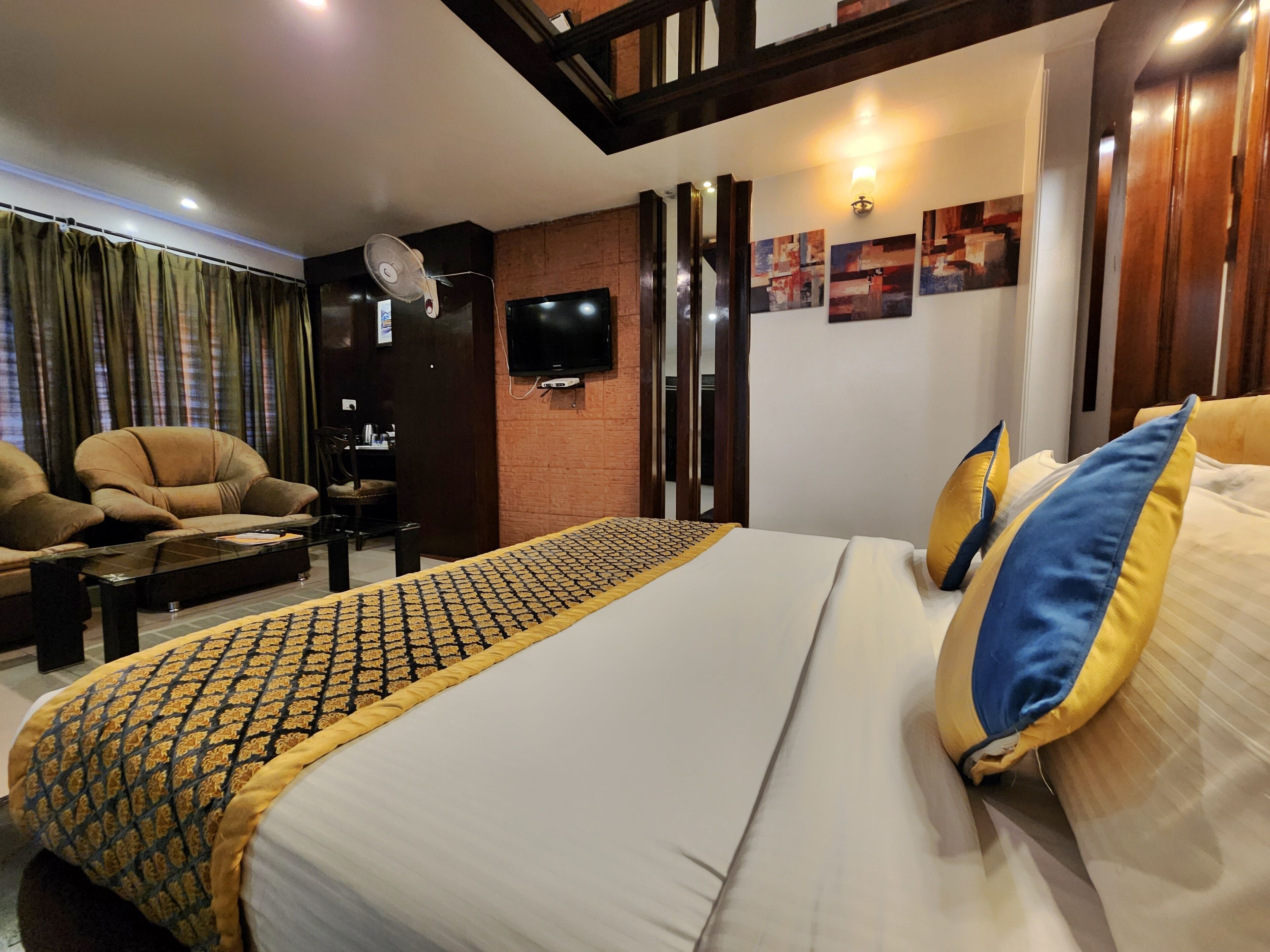 Una camera d'albergo con un letto grande, un divano, una televisione e una scrivania.
