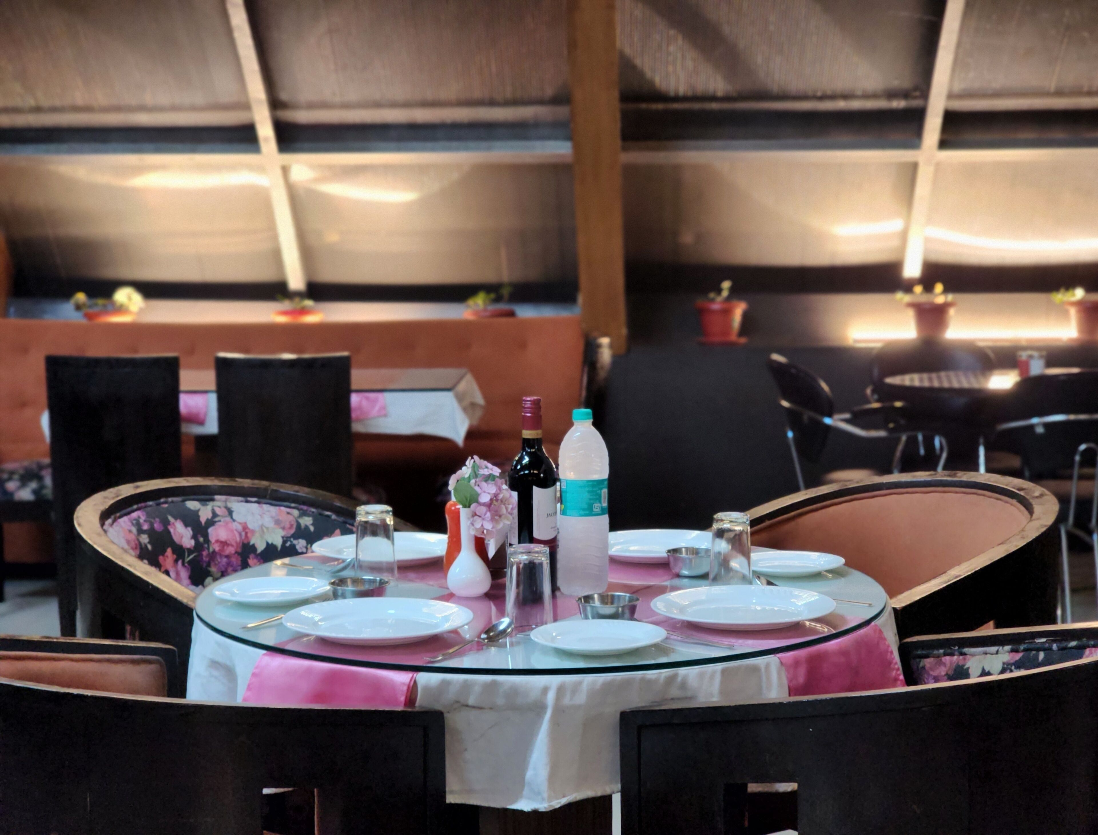 Une table ronde, prévue pour les repas, avec un plateau en verre, entourée de chaises.