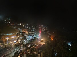 Un paisaje urbano nocturno con edificios iluminados y una calle concurrida.
