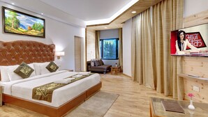 Quarto de hotel moderno com uma cama grande, uma televisão e vista para uma floresta pela janela.
