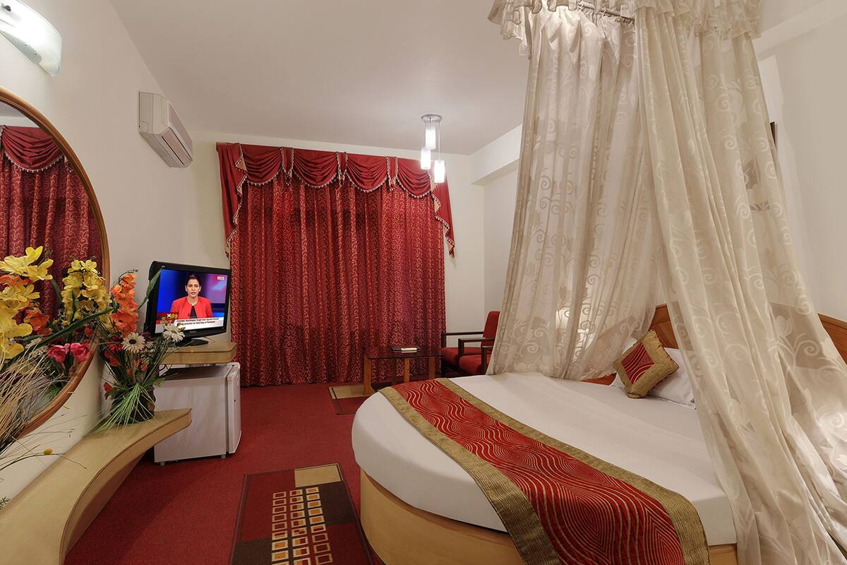 A hotel room with a bed, a television, a desk with a computer, and a chair.