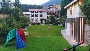 Um pátio de hotel com gramado bem cuidado, área de estar ao ar livre e um parquinho.