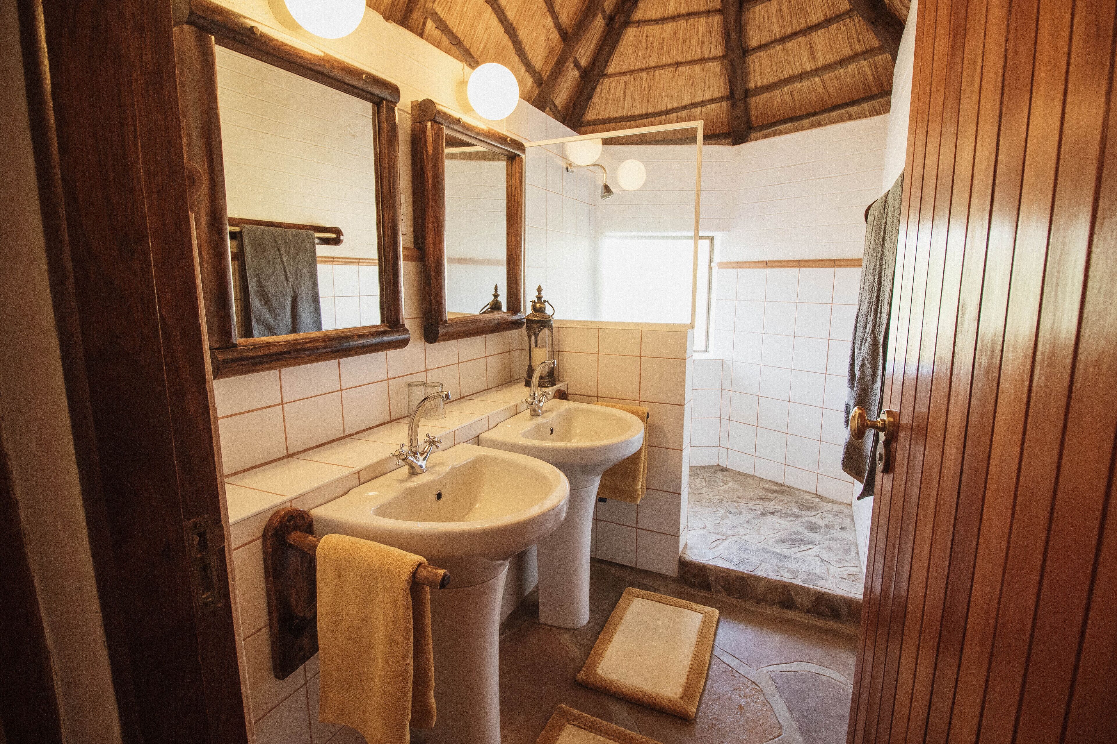 A bathroom with two sinks, a large mirror, and a shower area.