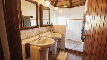 A bathroom with two sinks, a large mirror, and a shower area.