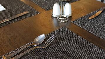 A dining table set with a placemat, a napkin, a spoon, a fork, and a knife.