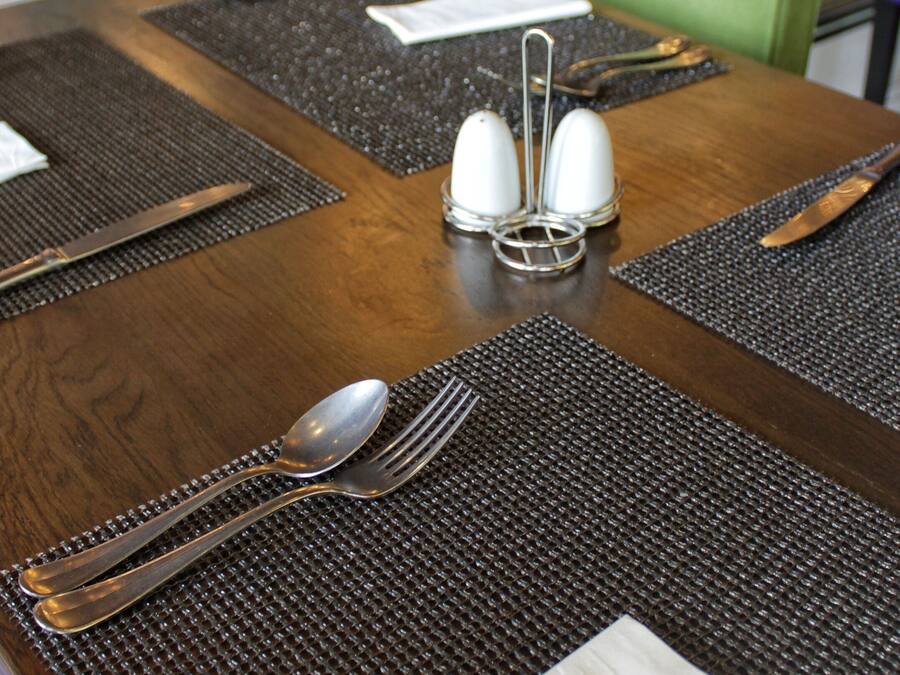 A dining table set with a placemat, a napkin, a spoon, a fork, and a knife.