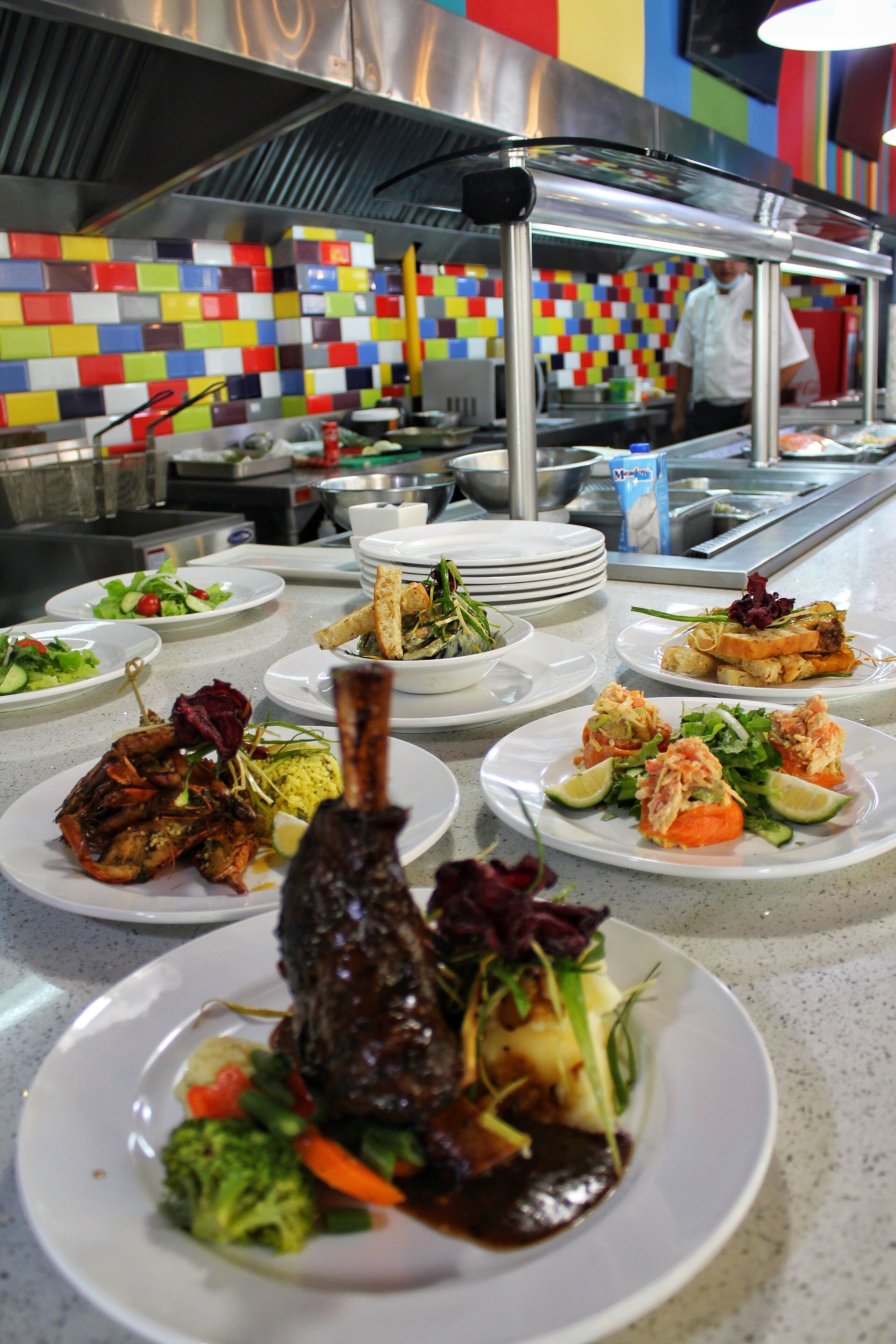 A buffet with various dishes, including seafood and salads, in a brightly colored kitchen area.