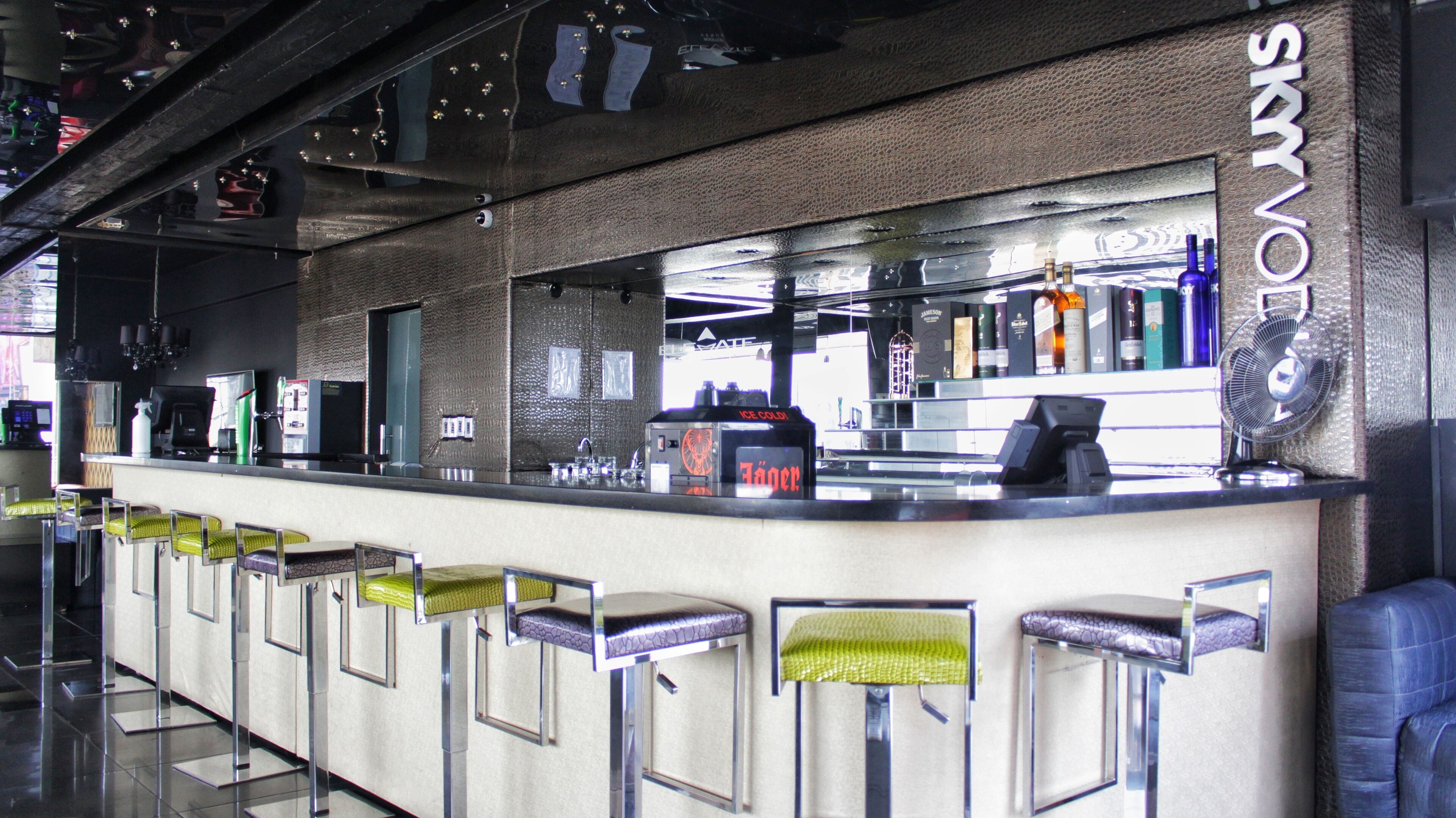 A bar area with a counter, stools, and a fan.