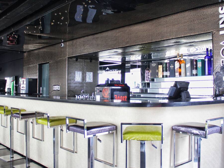 A bar area with a counter, stools, and a fan.