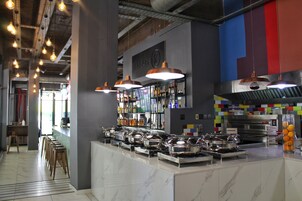 Un área de cocina moderna con electrodomésticos de acero inoxidable, una mesa de buffet y lámparas colgantes.