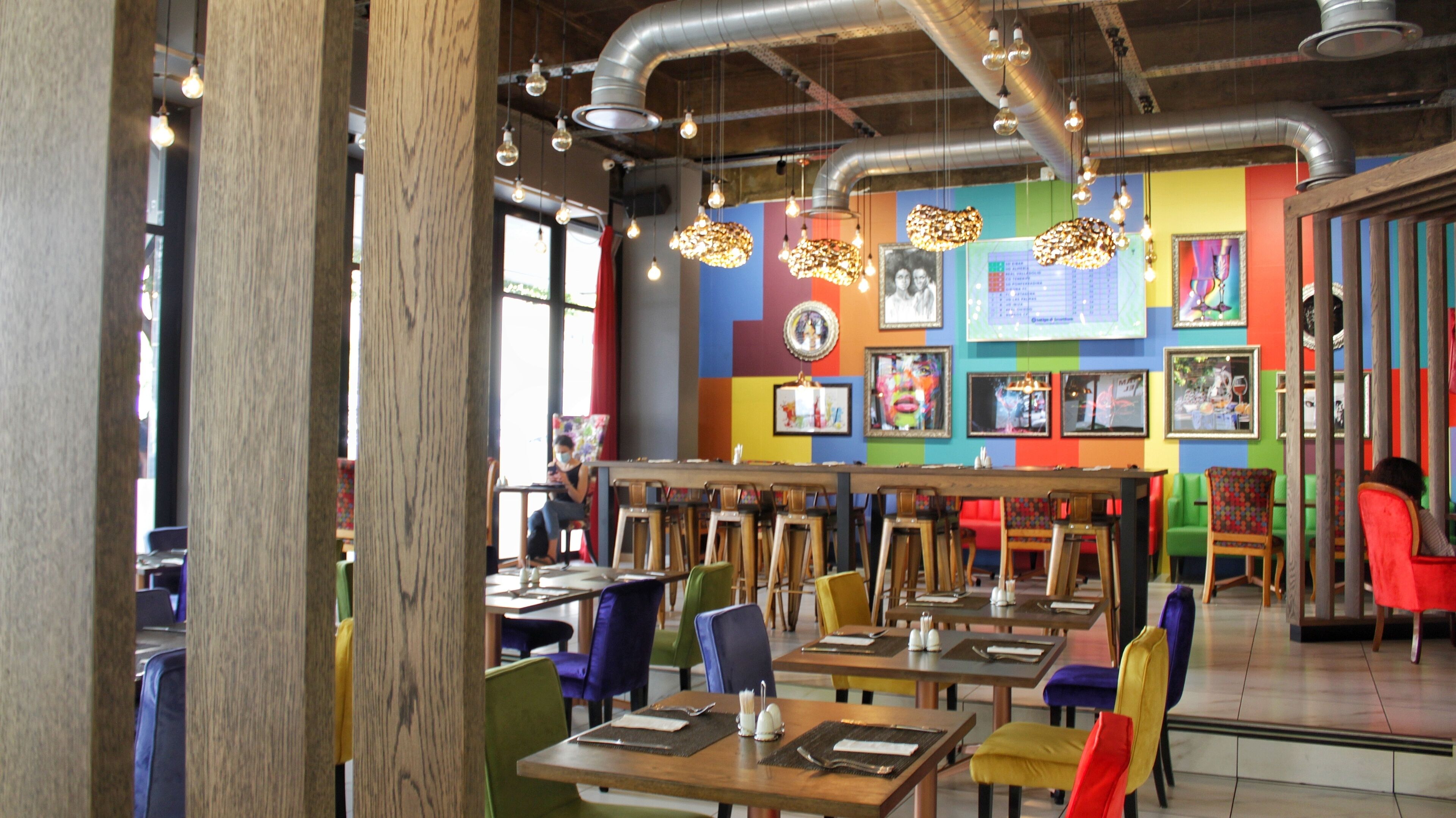 Un restaurante con un interior colorido, mesas y sillas de madera.