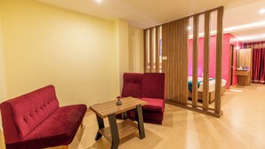 Una habitación con dos sofás rojos, una mesa de madera y un separador con listones verticales.