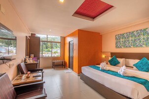Een hotelkamer met een groot bed, een bureau met stoel, en een raam met uitzicht.