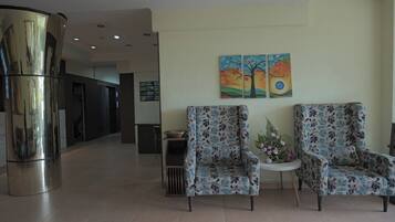 Un hall d’entrée avec deux fauteuils à motifs, une petite table sur laquelle est posé un vase, et un tableau accroché au mur.