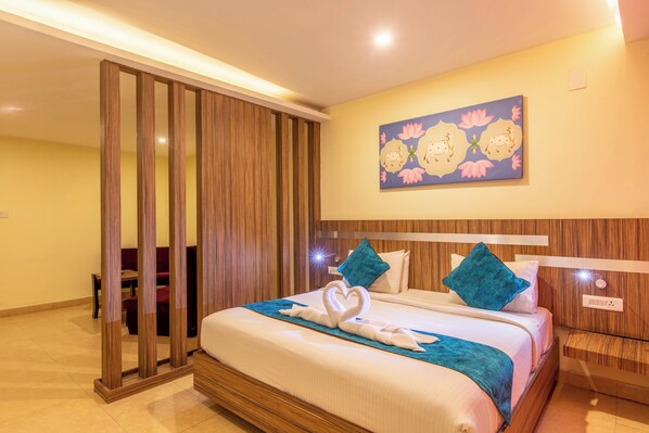 Habitación de hotel con cama, mesita de noche, separador de madera y un cuadro en la pared.