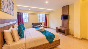 Ein Hotelzimmer mit Bett, Schreibtisch, Fernseher und einem fensterbepflanzten Fenster.