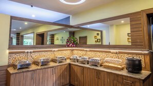 Ein Frühstücksbuffet mit mehreren Bereichen, einem großen Spiegel und einer dekorativen Blumenkomposition.