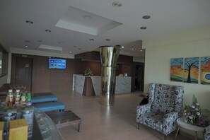 En modern hotellobby med en receptionsdisk, en sittgrupp och en stor, dekorativ pelare.