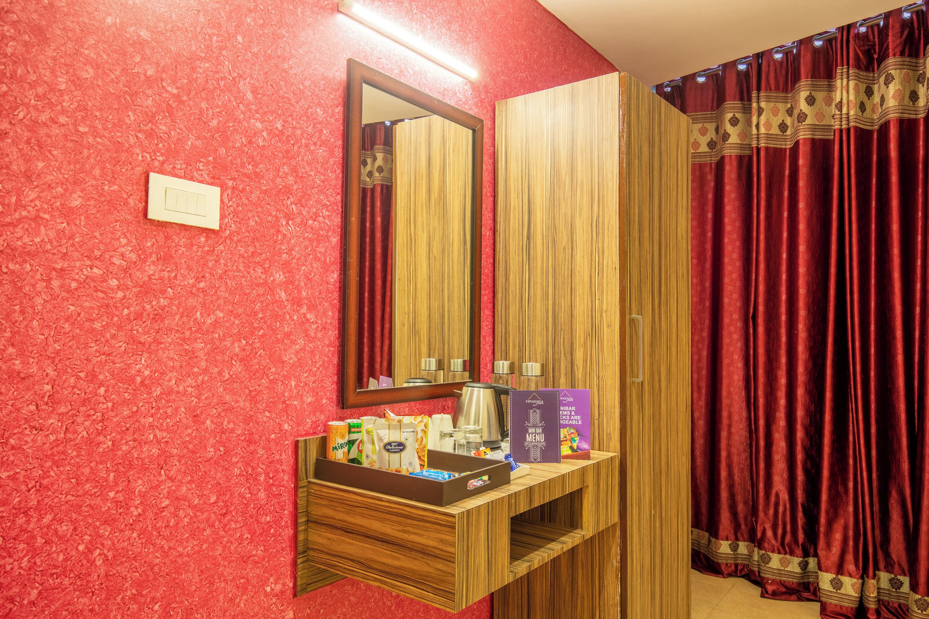 A hotel bathroom with a wooden vanity, a mirror, and a red curtain.