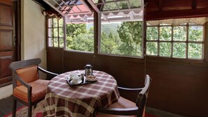 A cozy room with a checkered tablecloth, a wooden chair, and a window with a view of greenery.