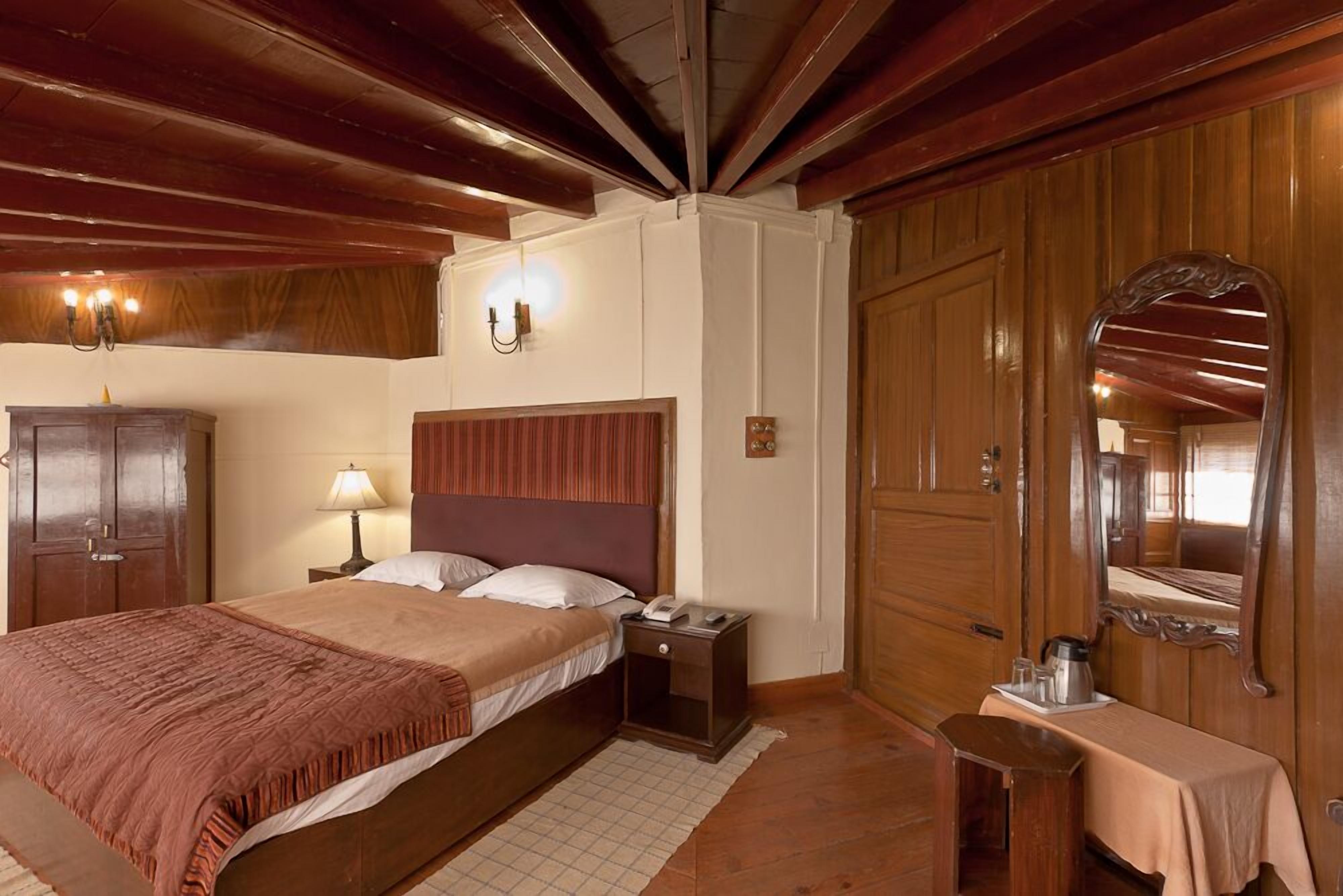 Un dormitorio con una cama grande, un armario de madera, una mesita de noche y un espejo.