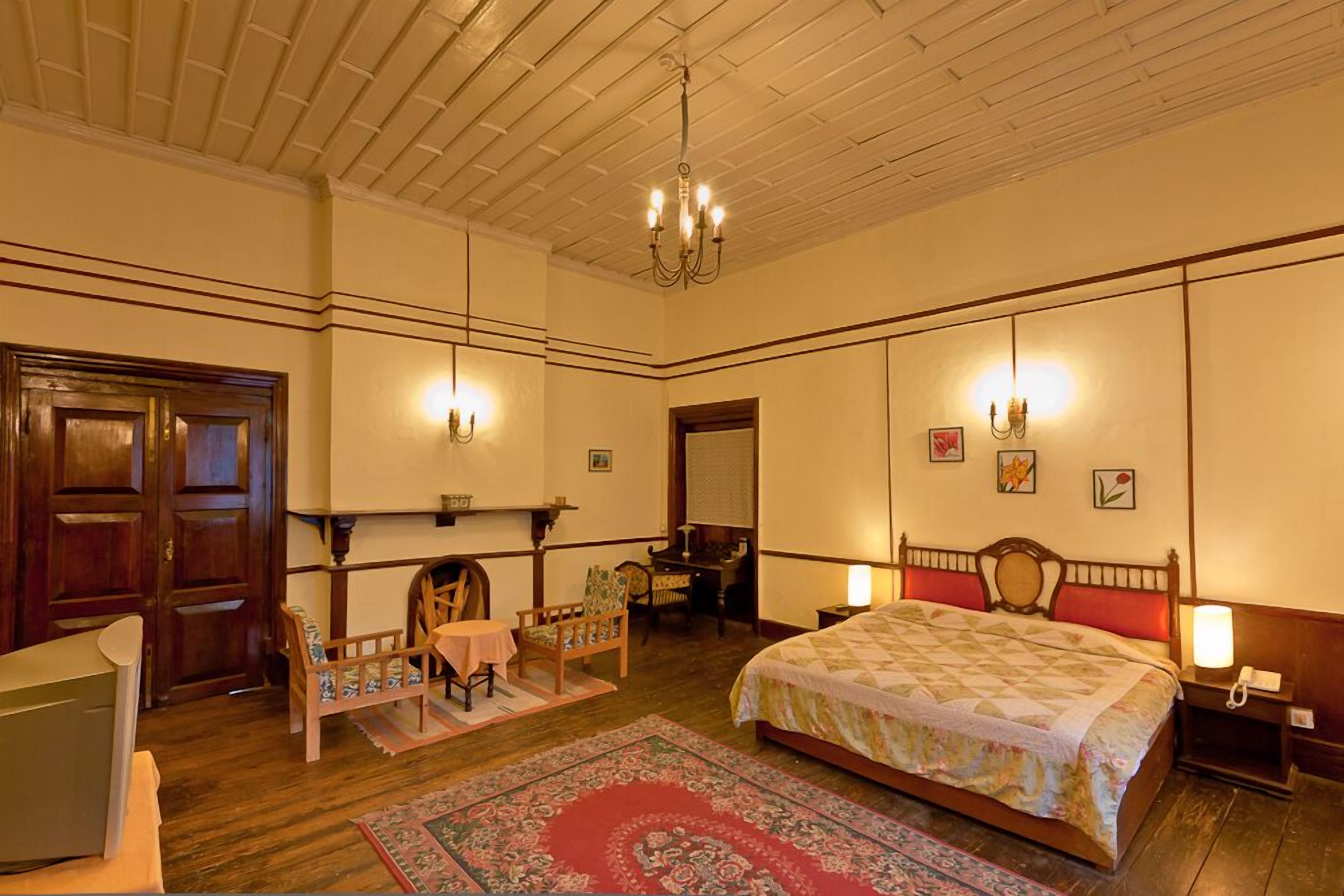 Een klassieke kamer met een groot bed, houten meubels en een kroonluchter.