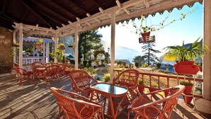 Un patio al aire libre con mobiliario de mimbre y macetas colgantes.