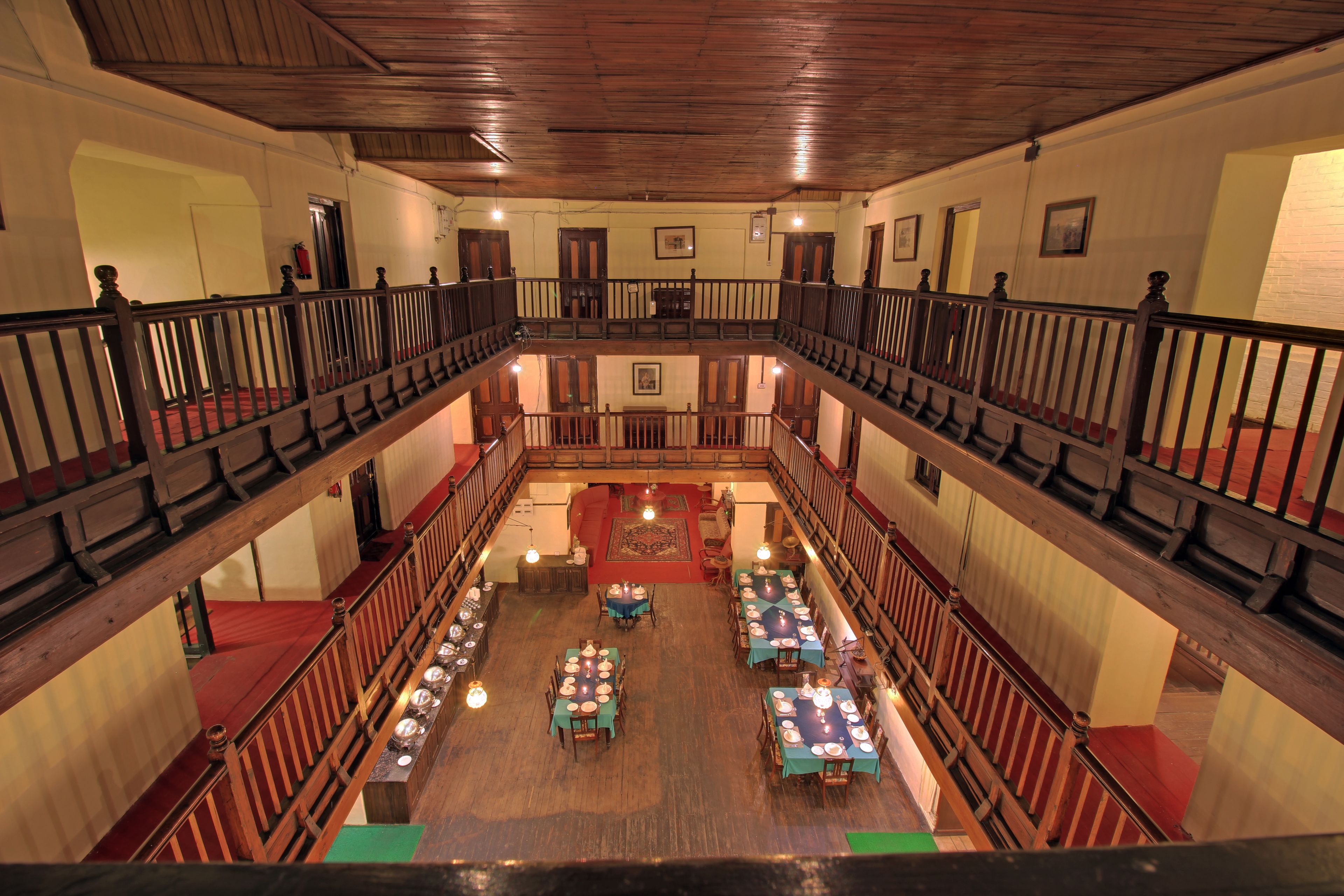 A multi-level hall with wooden railings and tables set up for dining.