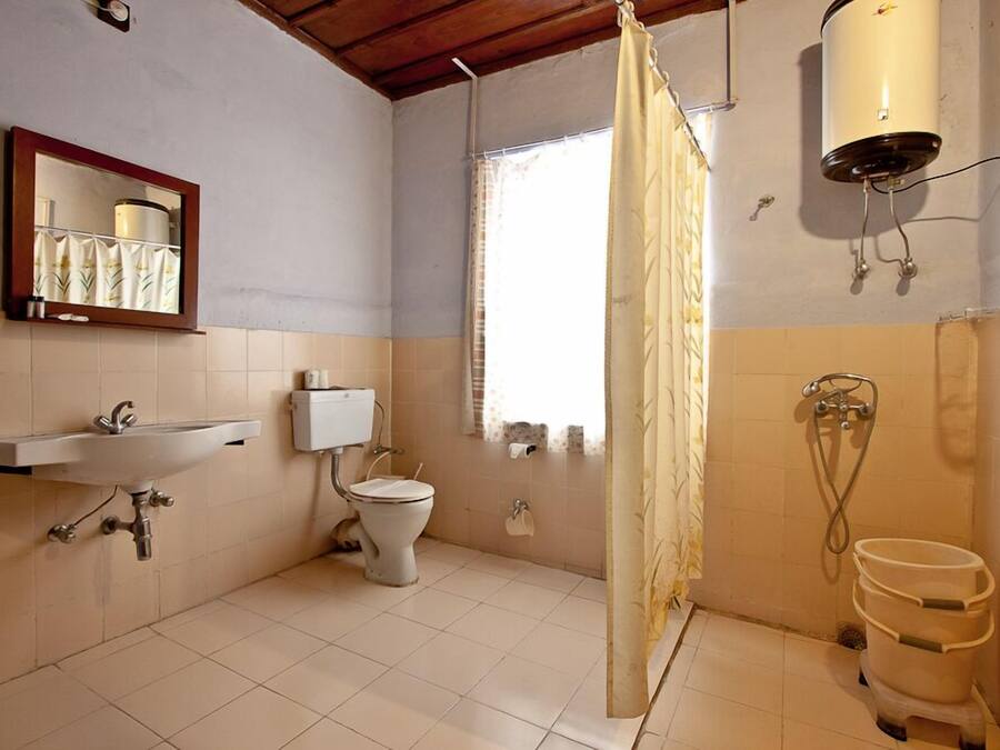 A bathroom with a toilet, sink, shower, and a window.