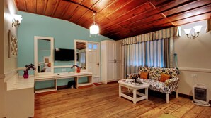 Una sala de estar con suelo de madera, un sofá, un televisor, un espejo y un techo con vigas de madera.