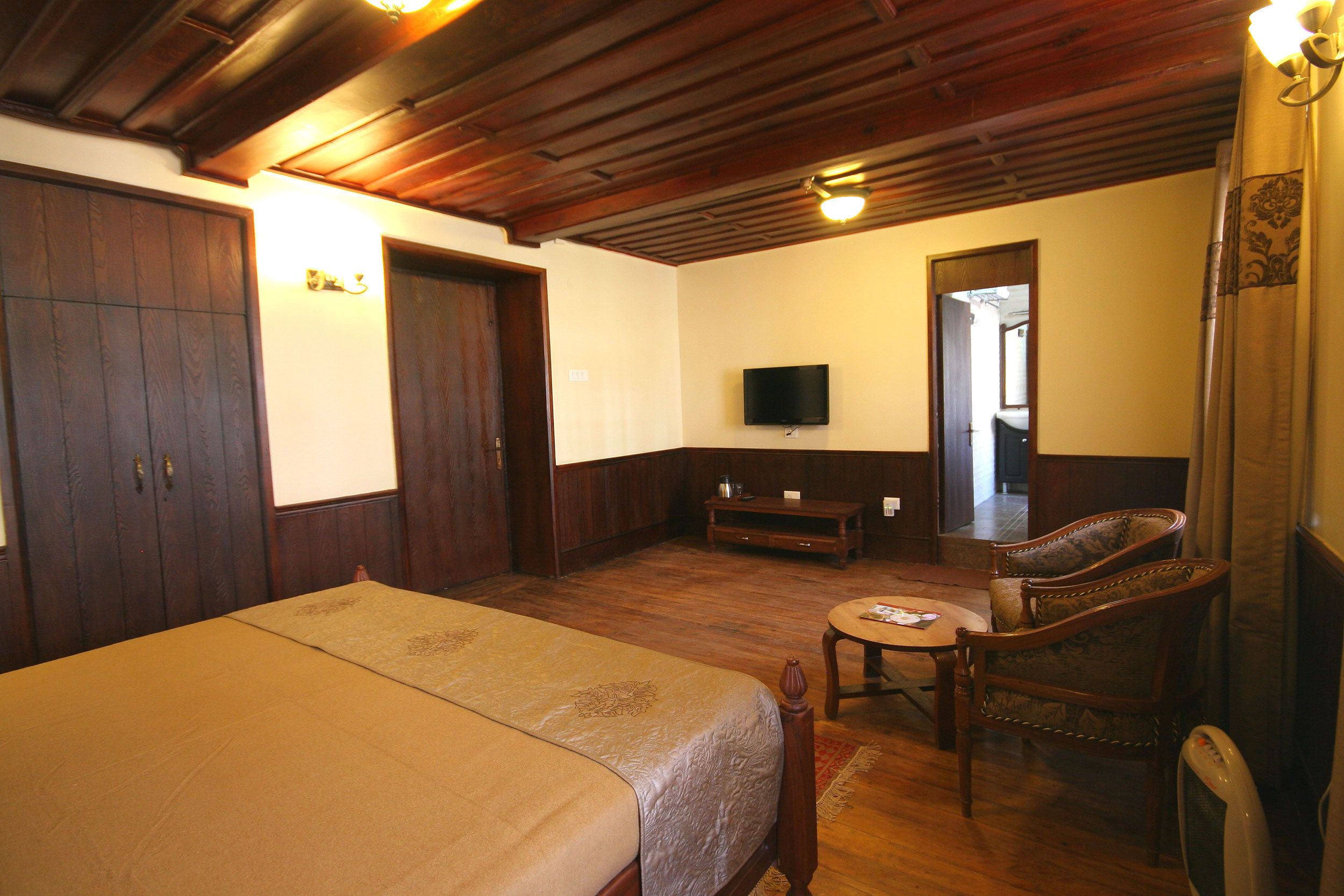 A hotel room with a bed, a television, a wooden ceiling, and a chair.