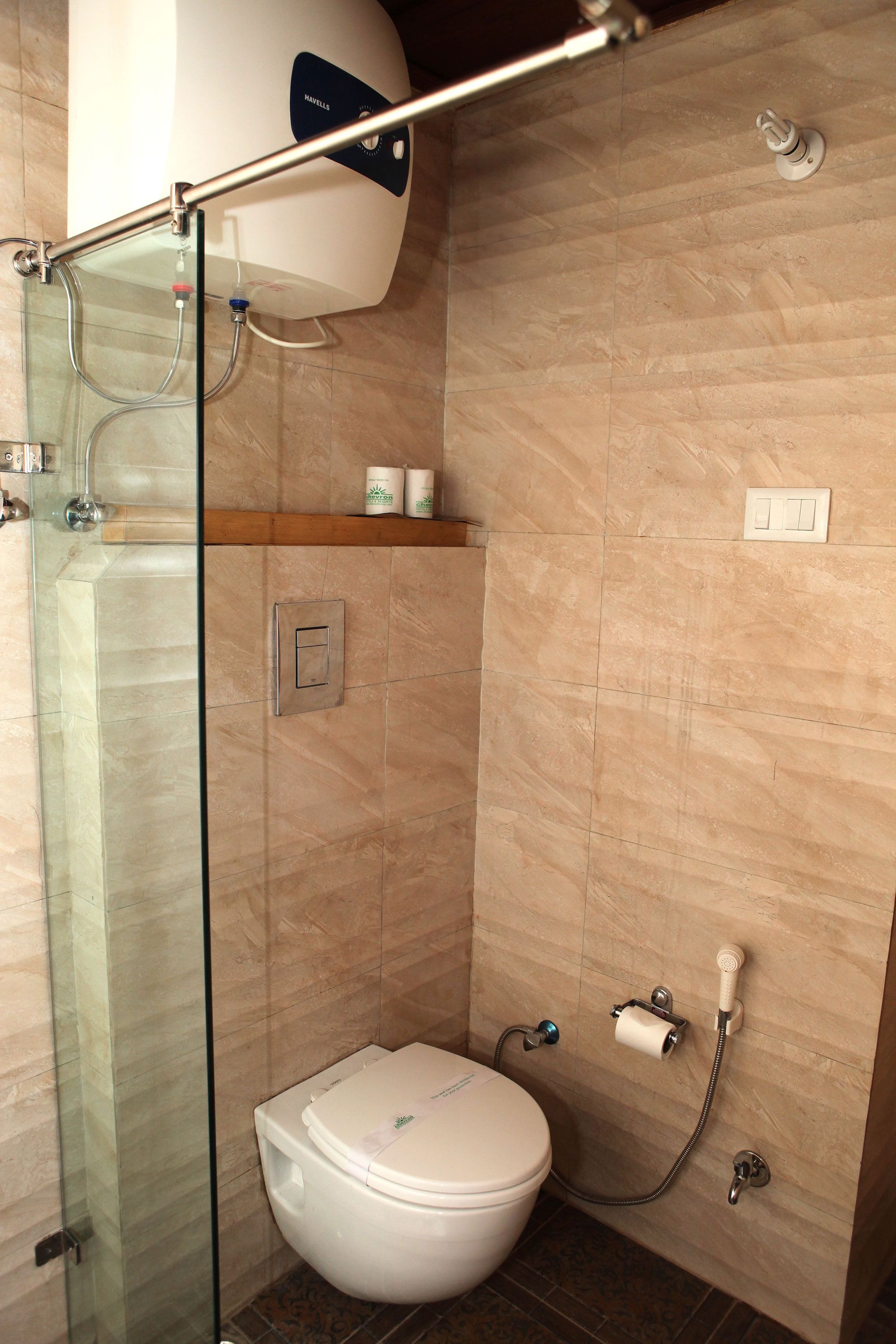 A modern bathroom with a glass shower enclosure, a toilet, and a built-in heater.