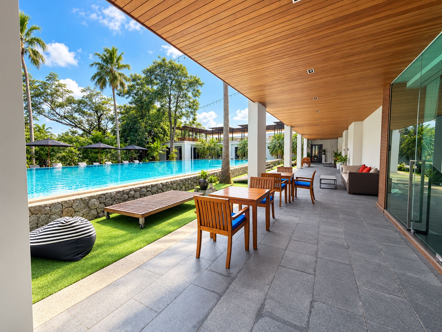 Zona de piscina moderna al aire libre con terraza de madera, asientos y vistas a la piscina.