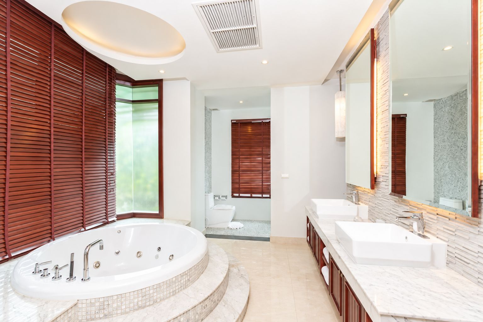 A modern bathroom with a large bathtub, two sinks, and a walk-in shower.