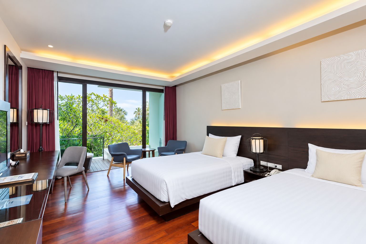 Ein Hotelzimmer mit zwei Betten, einem Schreibtisch, einem Stuhl und einem großen Fenster mit Blick auf Grünflächen.