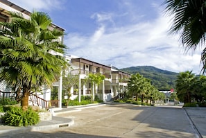 A resort with a paved walkway, palm trees, and a mountain backdrop. - Club Wyndham Patong Hill, Trademark Collection by Wyndham (Patong)