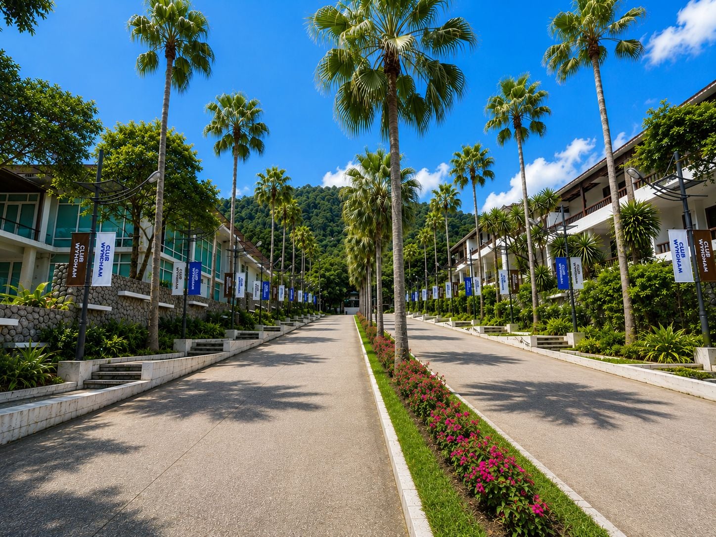 Eine Hotelstraße mit Palmen, blauem Himmel und Flaggen.