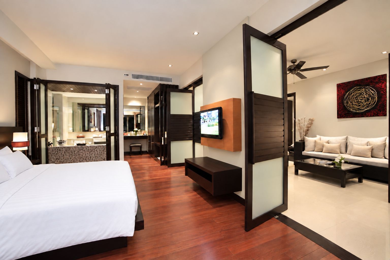 A hotel room with a bed, a TV, a sofa, and a coffee table.