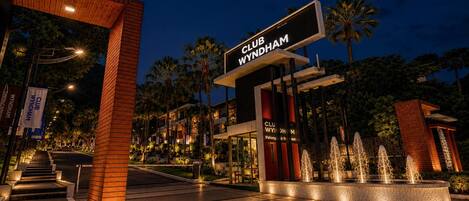 A Club Wyndham entrance with a modern design, palm trees, and a well-lit pathway leading to the building.